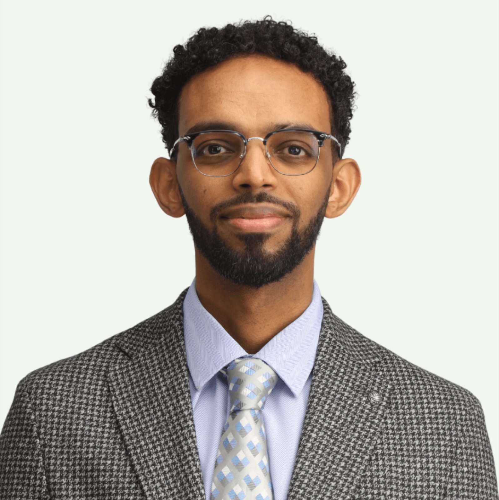 Portrait of Michael Hailemariam in a grey checked blazer, light blue shirt and patterned tie